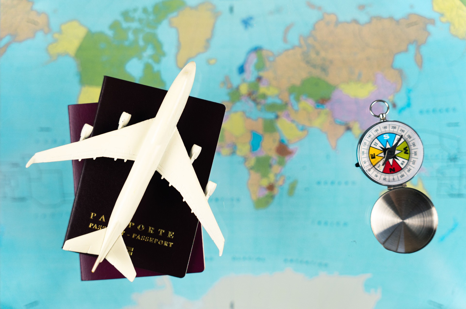 Passports, airplane model and compass on world map background, planning a trip around the world